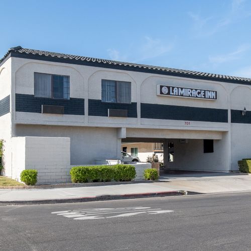 The image shows a two-story building with the signage "La Mirage Inn" on the facade and a nearby street.