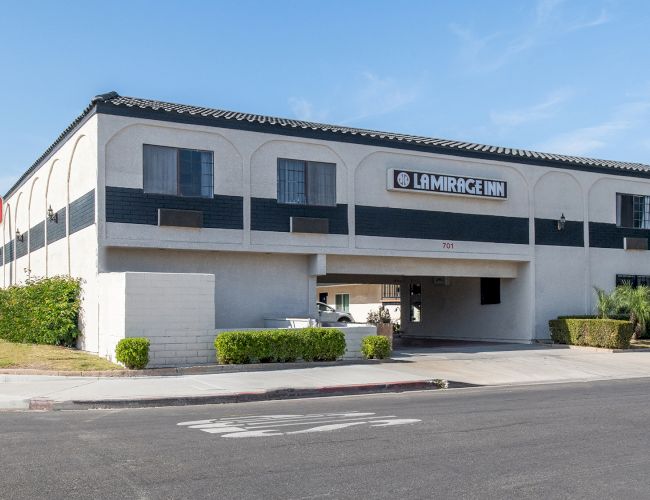 The image shows a two-story building with the signage "La Mirage Inn" on the facade and a nearby street.