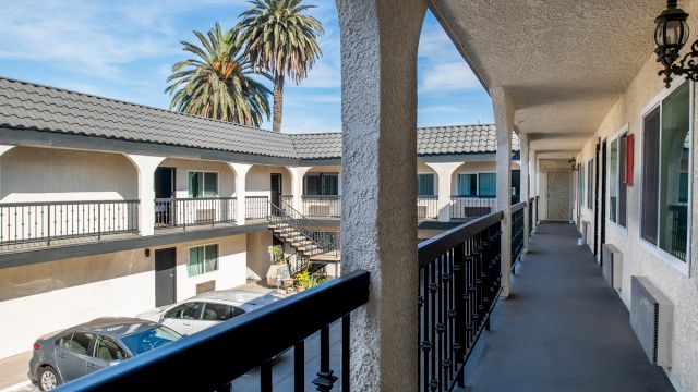 A view of a hotel's balcony with a parking lot and palm tree in the background.