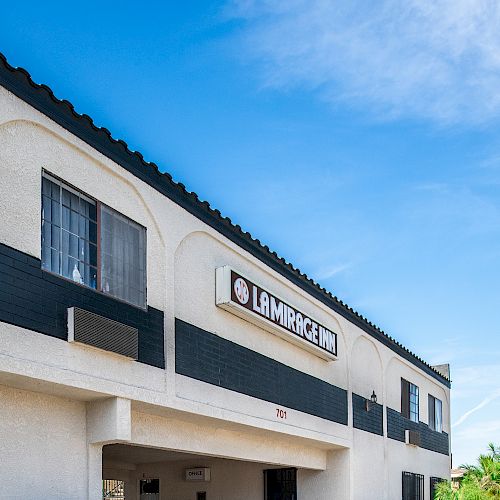 A building with the sign "La Mirada" under a blue sky, featuring palm trees and a decorative facade.