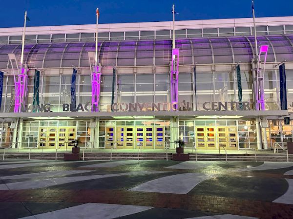 The image shows the exterior of the Long Beach Convention Center, with purple lighting illuminating the front entrance.