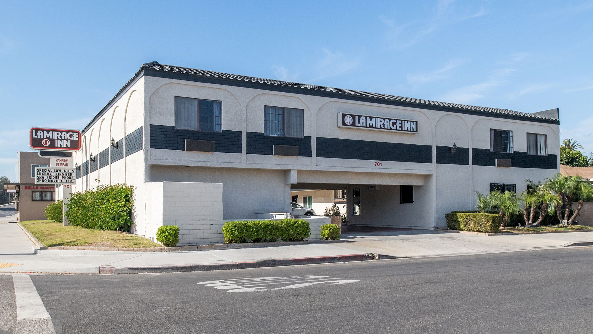 The image shows a two-story building with "La Mirada Inn" signage, featuring an entrance, windows, and some greenery around.