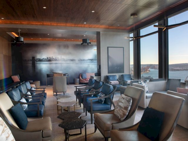A lounge area with seating and large windows showing a city view.